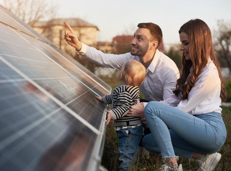 Junge Familie schaut sich Solaranlage auf einer Wiese an