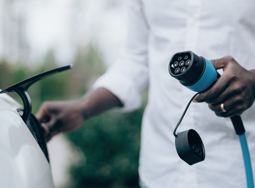 Mann hält Ladekabel für E-Auto in der Hand