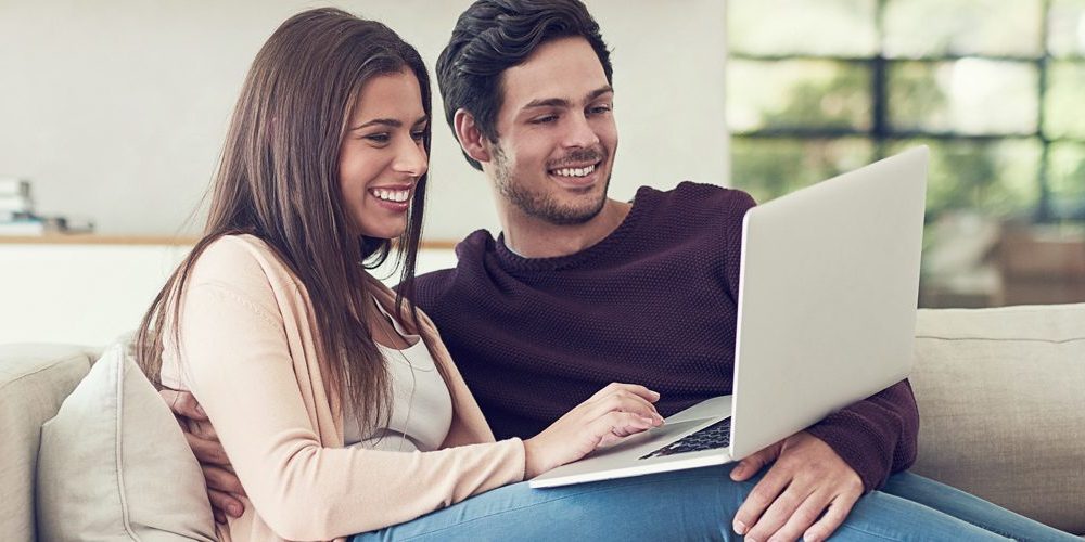 Junges Paar mit Laptop auf Sofa