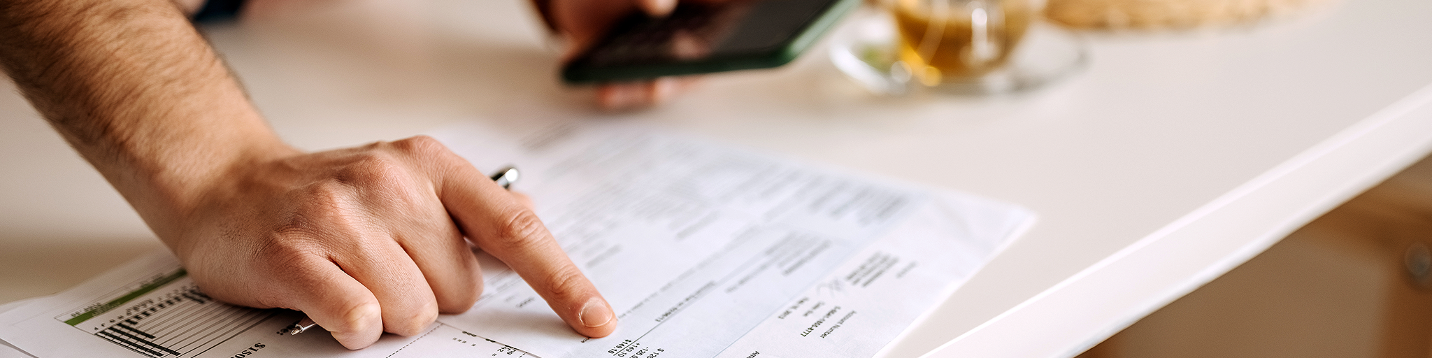 Foto: Mann prüft Unterlagen auf einem Tisch